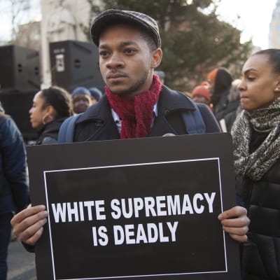 En man håller upp en skylt där det står "vit makt är dödligt".
