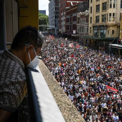 Henklö katselee alas kadulle jossa tuhansittain ihmisiä demonstroimassa.