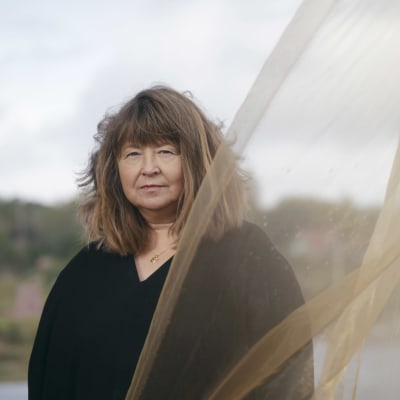 Författaren Carina Karlsson med en slöja som böljar i vinden.