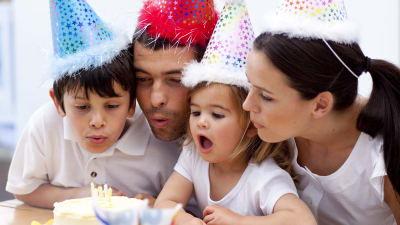 En familj som blåser ut ljus på en tårta.  