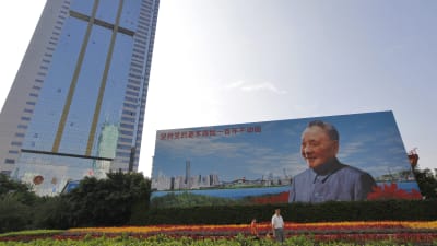 En kinesisk familj i staden Shenzhen går förbi en jättelik av affisch av Deng Xiaoping, som genomförde ekonomiska reformer i Kina i början av 1980-talet.