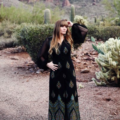 Sångaren Courtney Marie andrews står i en öken med kaktus bakom.