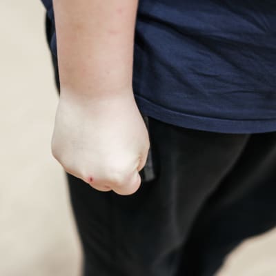 Ett barn ar handen i en knytnäve. 