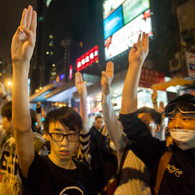 demonstranter håller upp fingrar i Hongkong.