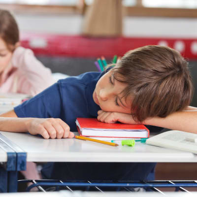 en pojke ligger på en skolbok