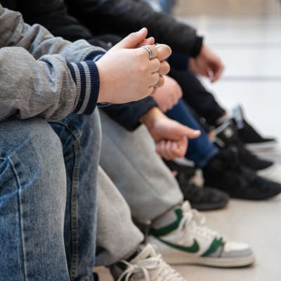 Anonyymeja 7.-luokkalaisia poikia istumassa Lauritsalan koulun käytävällä.