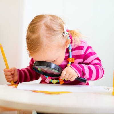 Ett barn tittar på ett papper genom ett förstoringsglas.