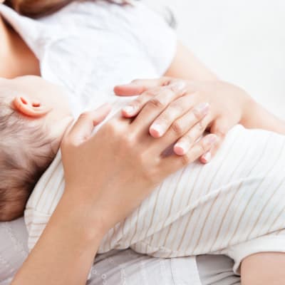 ett spädbarn som vilar på mammans bröstkorg. Mamman håller sina händer om den lilla barnkroppen