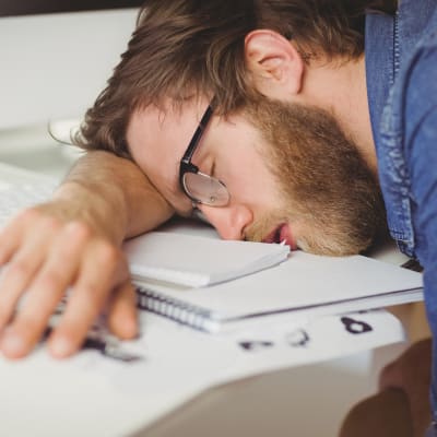Man sover lutad mot sitt arbetsbord