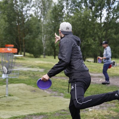 En man kastar en frisbee mot en korg.