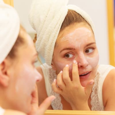 Kvinna applicerar ansiktsmask.