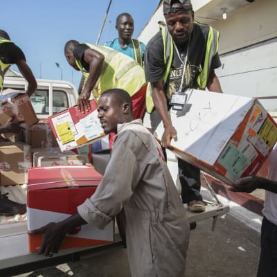 Liberiska män lastar av material som ska skydda mot Ebola.