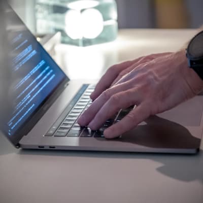 Närbild: En man skriver på en bärbar dator.