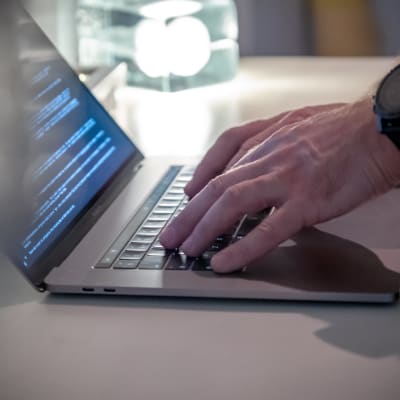 Närbild: En man skriver på en bärbar dator.