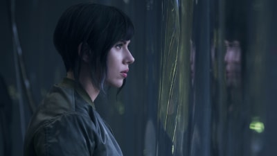 Major (Scarlett Johansson) står invid ett mörkt fönster och ser ut.