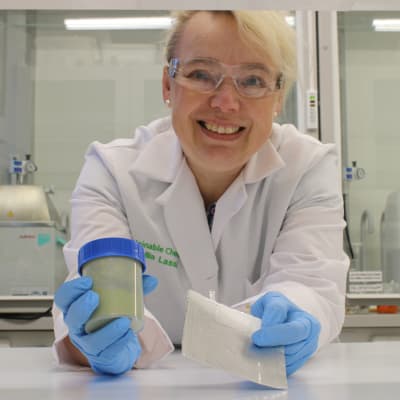Professori ja tekniikan tohtori Ulla Lassi laboratoriossa kädessään kumihanskat.