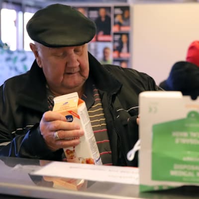 Esko Vepsäläinen pakkaamassa maitotuotteita kassiin ViaDia Mikkelin ruoka-avussa.
