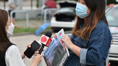 En reporter från Apple Daily intervjuar en person som stöder tidningen utanför Apple DAilys högkvarter.
