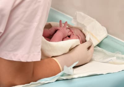 En nyförlöst bebis som en skötare håller om på ett skötbord.