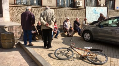 Pensionärer träffas på torget i Veles i Makedonien. En har lämnat sin cykel liggande på trottoaren.