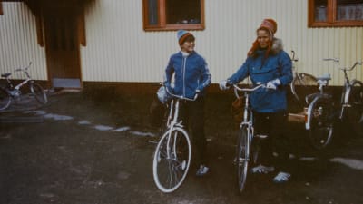 Kuvassa on Priitta Pöyhtäri-Tröen 13-vuotiaana äitinsä kanssa. Molemmilla on siniset takit ja pyörät.