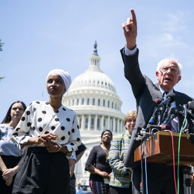 Bernie Sanders framför mikrofoner utanför kongressen med pekfinger i luften.