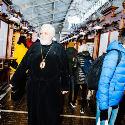 Arkkipiispa Leo kävelee Helsingin vanhassa kauppahallissa.