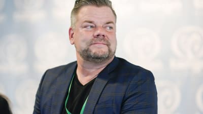 Jari Sillanpää med blå kostym och skägg. 