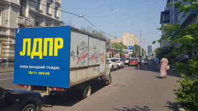 En lasbil i stadsmiljö. På lastbilen står det på ryska "LDPR, ta kontakt per mejl".