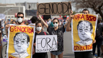 Demonstranter går på gatorna i Brasilia i Brasilien. De håller upp skyltar där det står "folkmord Bolsenaro".