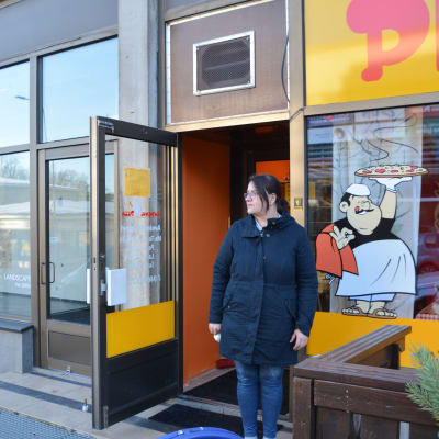 kvinna står i dörren till en pizzeria