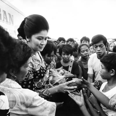 Filippiinien itsevaltiaan Ferdinand Marcosin vaimo Imelda tapaa lapsia yleisötilaisuudessa vuonna 1970. Kuva on mustavalkoinen.