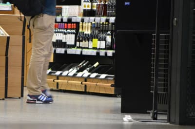 En man står framför en vinhylla.