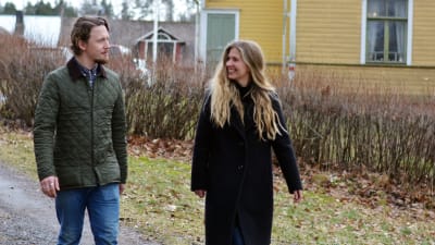 Oscar Gräsbeck och Ida Söderström går utanför ett stort gult trähus.