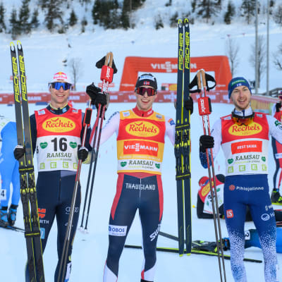 Vinzenz Geiger,  Jarl Magnus Riiber och Ilkka Herola på prispallen i världscupen i december 2021.