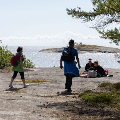 Retkeilijät kävelemässä ja istumassa kalliolla meren rannalla Ulko-Tammiossa.