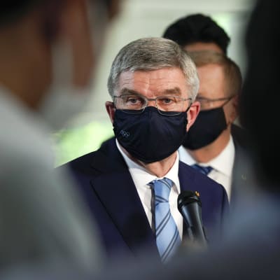 IOK:s ordförande Thomas Bach med munskydd, ser bekymrad ut