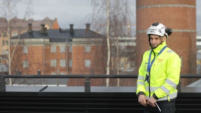 En man i varseljacka och skyddshjälm står på ett tak i Vasa.