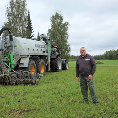 Maanviljelijä Jukka Leikkonen. Taustalla traktori, johon kiinnitetty karjalannan levitin.