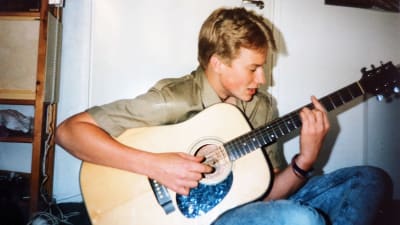 Programledaren Mårten Svartström som ung, spelar på sin gitarr. 
