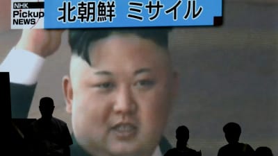 Fotgängare i Tokyo passerar en TV-skärm som visar Kim Jong-un 4.7.2017