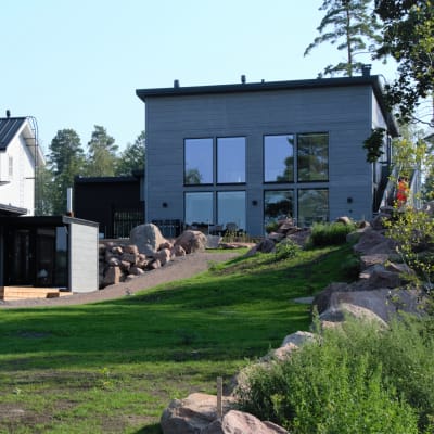 Nybyggda trähus med en gräsmatta i förgrunden.