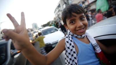 Palestinsk pojke visar segertecken under firandet av eldupphöret i Gaza.