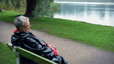 Författaren Ann-Mari Lindberg sitter på en bänk och tittar ut mot havsviken intill Lappvikens sjukhus.