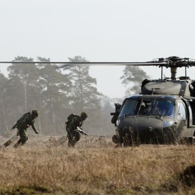 Soldater springer till en helikopter.