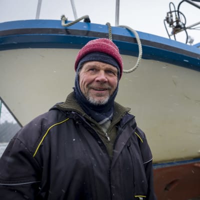 Helsinkiläinen ammattikalastaja Kai Ilves,  jäidensulamista odottavan veneensä edustalla.