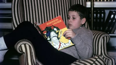 En ung kille läser "Robinson Crusoe".