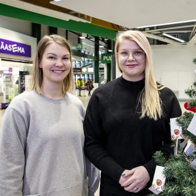Kotkan nuorkauppakamarin projektipäälliköt Laura Värtö ja Sonja Hirvasniemi joulupuun vieressä.