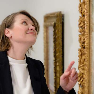 Sara Hildenin taidemuseon kokoelmapäällikkö Maria Laine tutkii koristeellista kullattua kehystä. 
