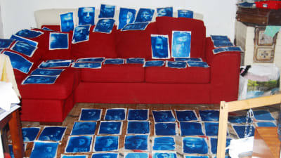 konstbild med blå porträtt på röd soffa